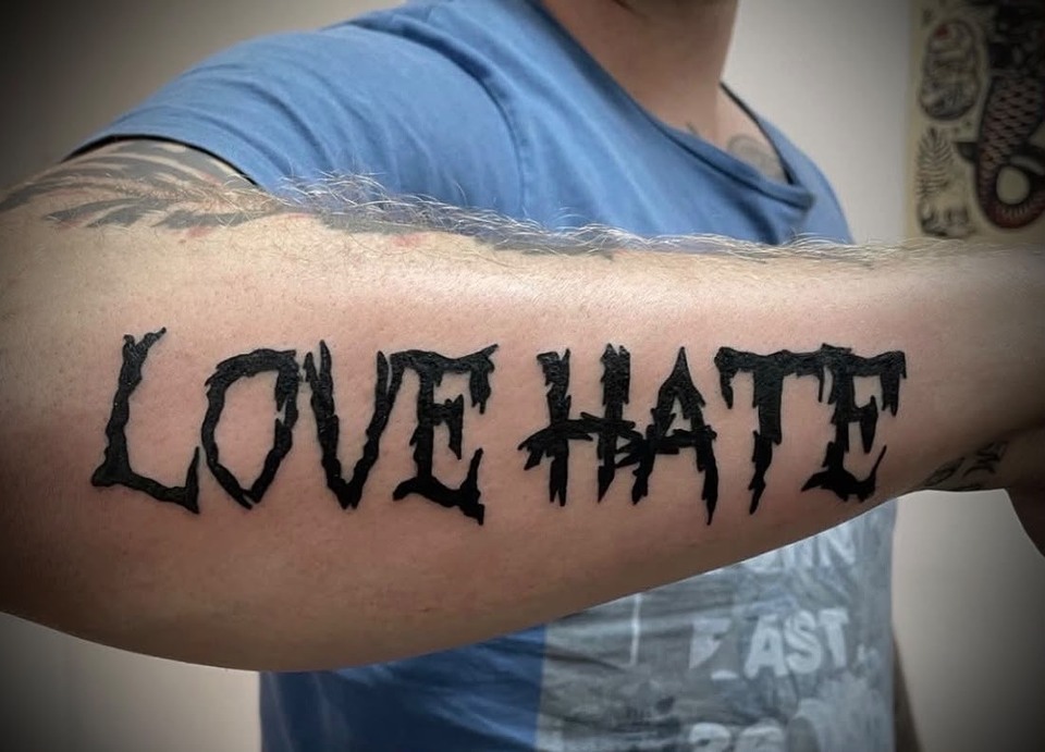 Markanter schwarzer Schriftzug Love Hate auf der Innenseite eines ausgestreckten Unterarms.